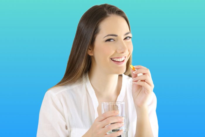 Woman taking an AHCC supplement with a glass of water